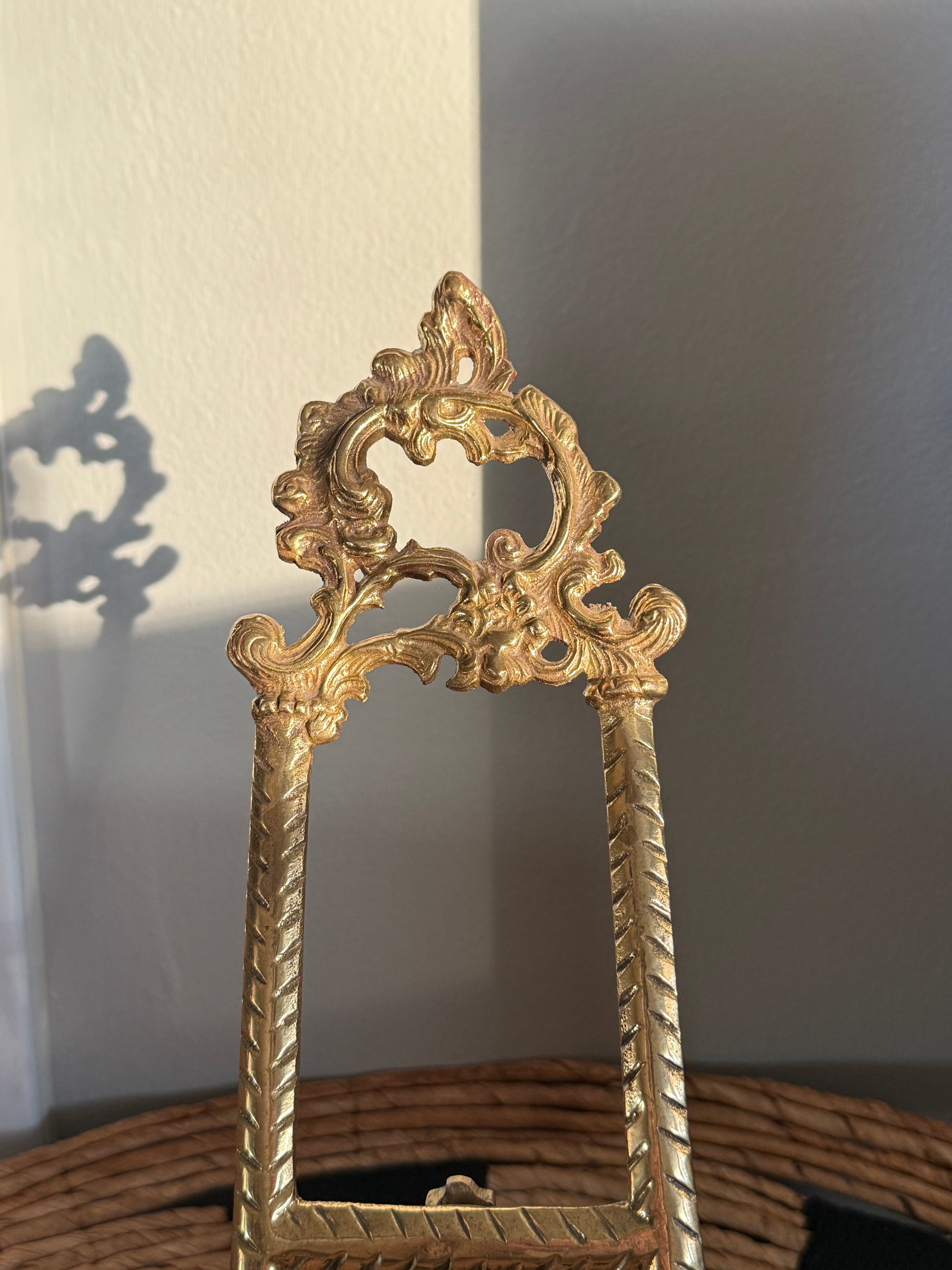Decorative gold mirror with intricate design against a plain wall.