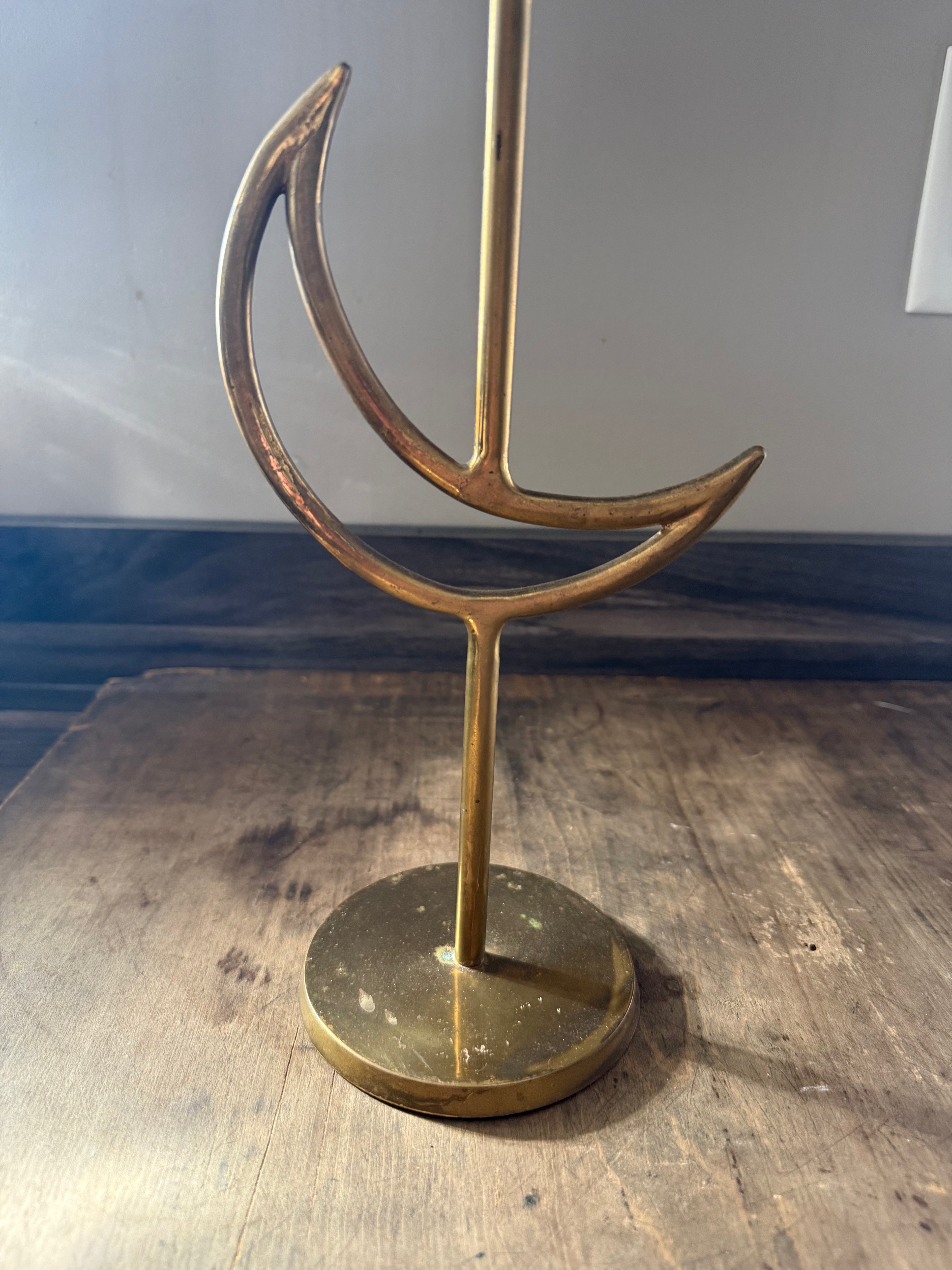 Brass crescent moon stand on a wooden surface with a neutral background