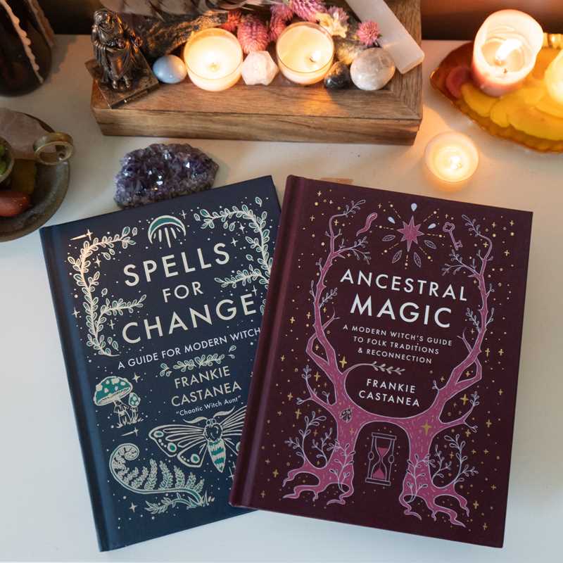 Two books titled 'Spells for Change' and 'Ancestral Magic' on a table with candles and crystals.