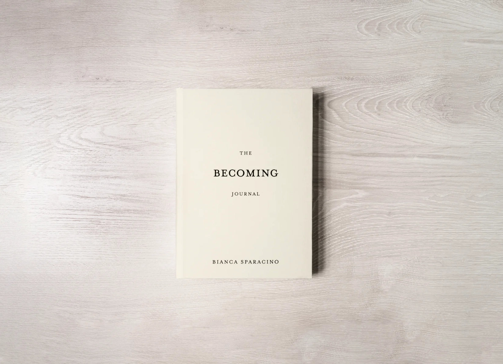 Book titled 'The Becoming Journal' by Bianca Sparacino on a wooden surface