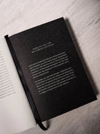 Black journal on a light wooden surface with text on the cover