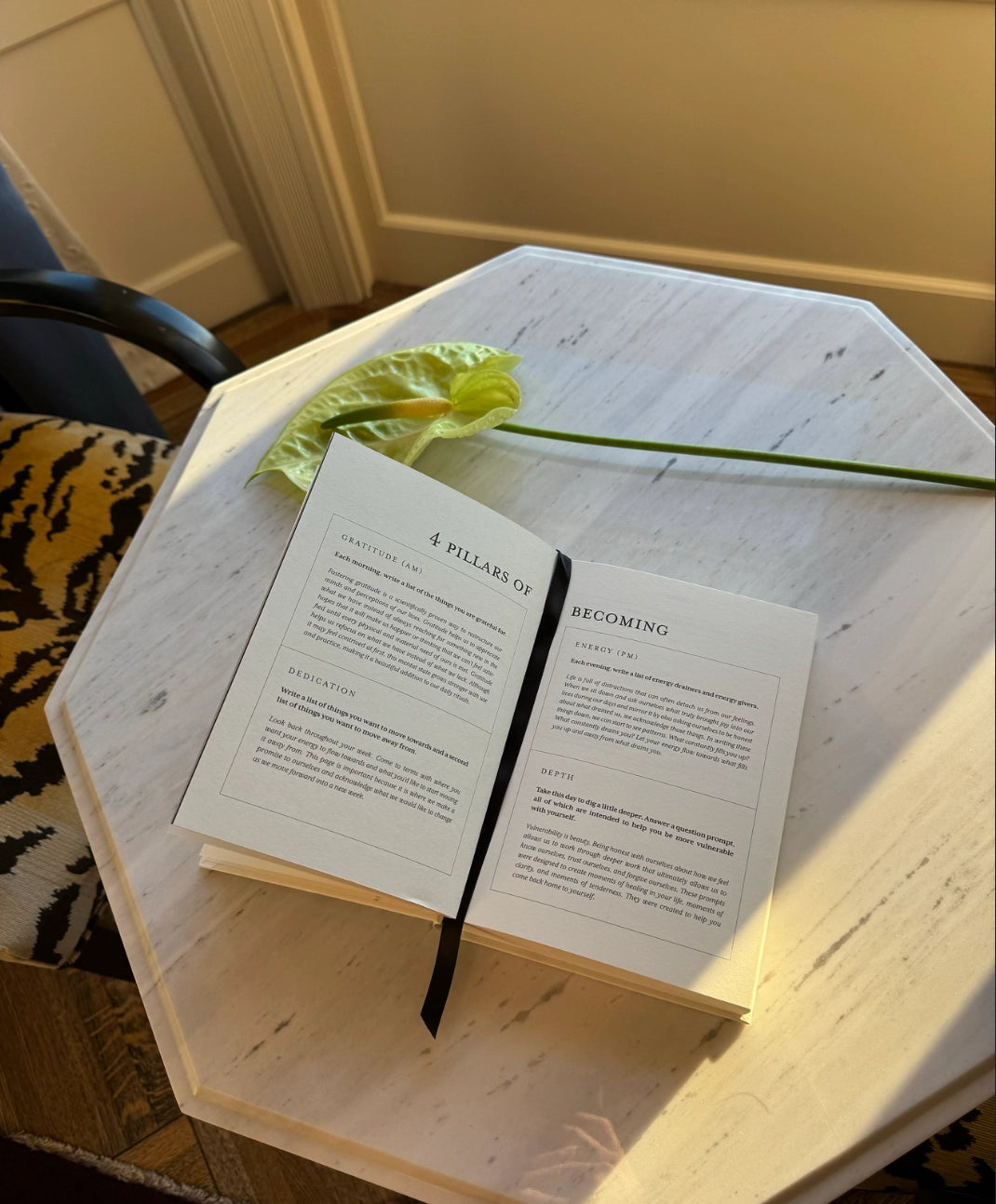 Open book on a hexagonal wooden table with a plant leaf on top