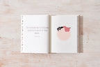 Open book with a motivational quote and illustration on a wooden surface
