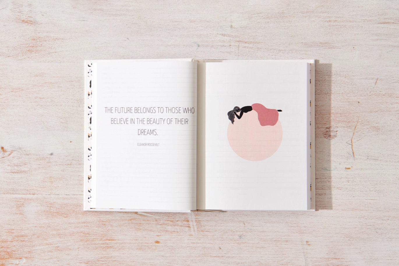Open book with a motivational quote and illustration on a wooden surface