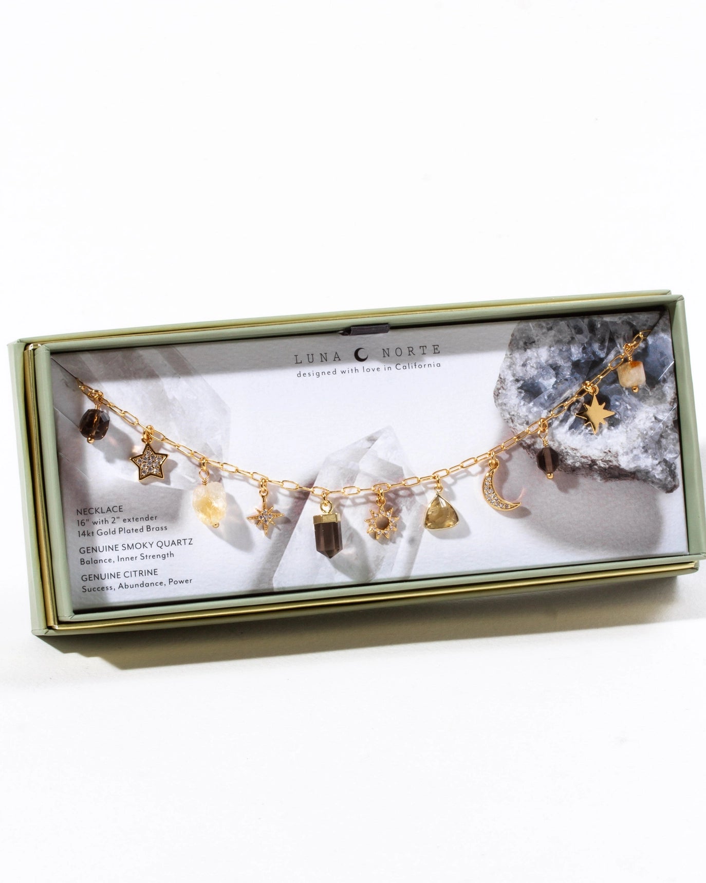 Jewelry box with a gold necklace featuring various charms on a white background