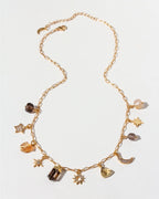 Gold necklace with various charms on a light gray background