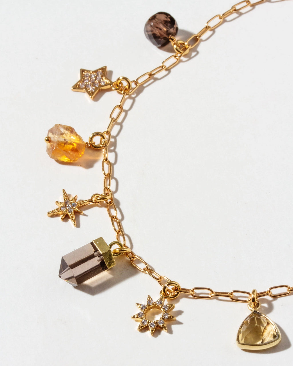 Gold bracelet with various charms on a white background