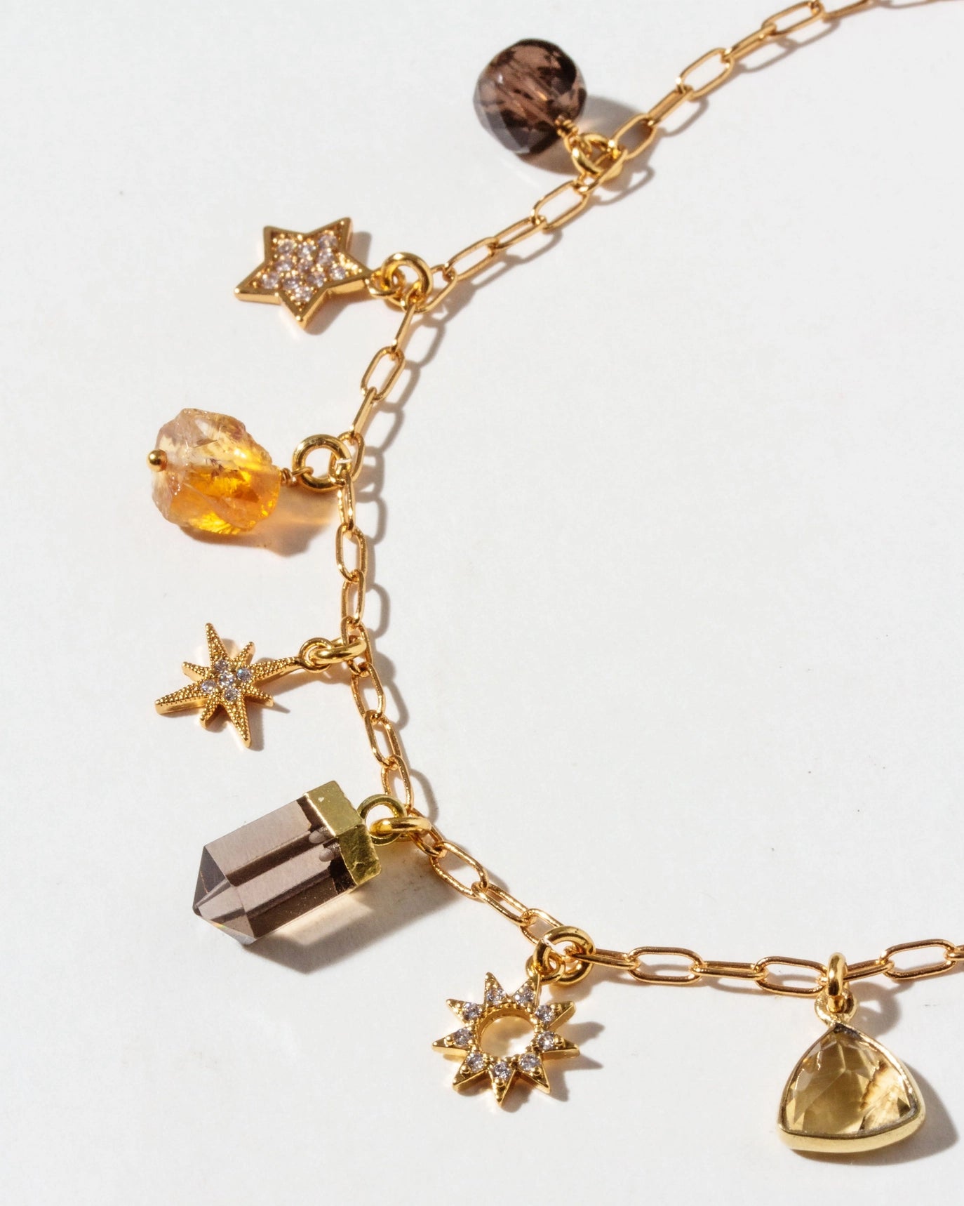 Gold bracelet with various charms on a white background
