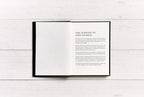 Open book with text on a white wooden surface