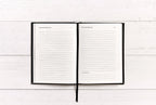 Open notebook with lined pages on a white wooden surface