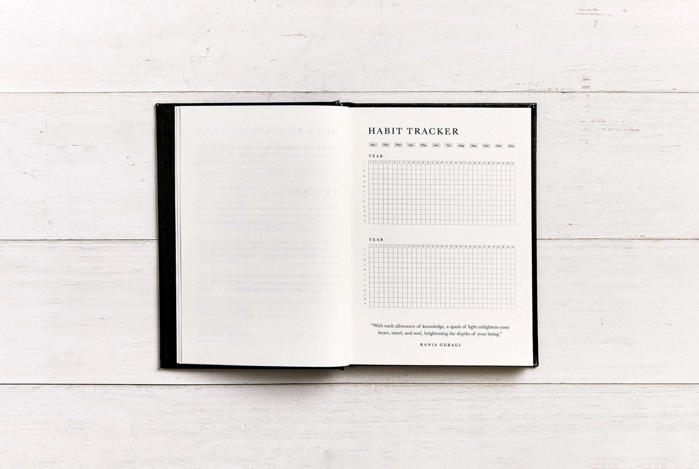 Habit tracker book open on a white wooden surface
