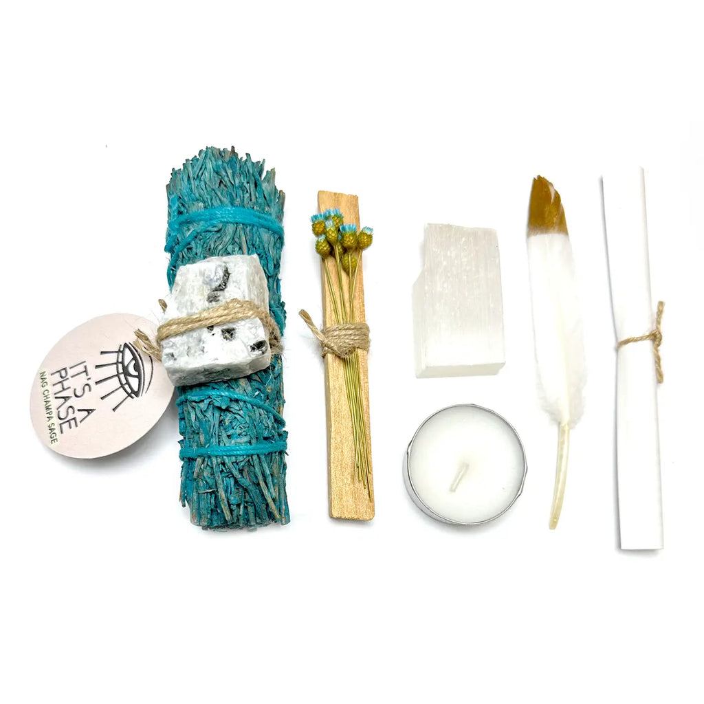 Set of smudging tools including sage, feather, candle, and soap on a white background