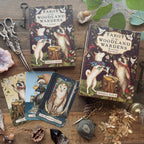 Tarot cards titled 'Tarot of the Woodland Wardens' by Jessica Roux on a wooden surface with nature-themed decor.